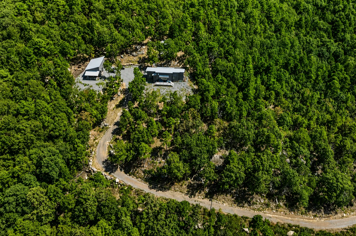 Top-down aerial of the home tucked into the wooded property