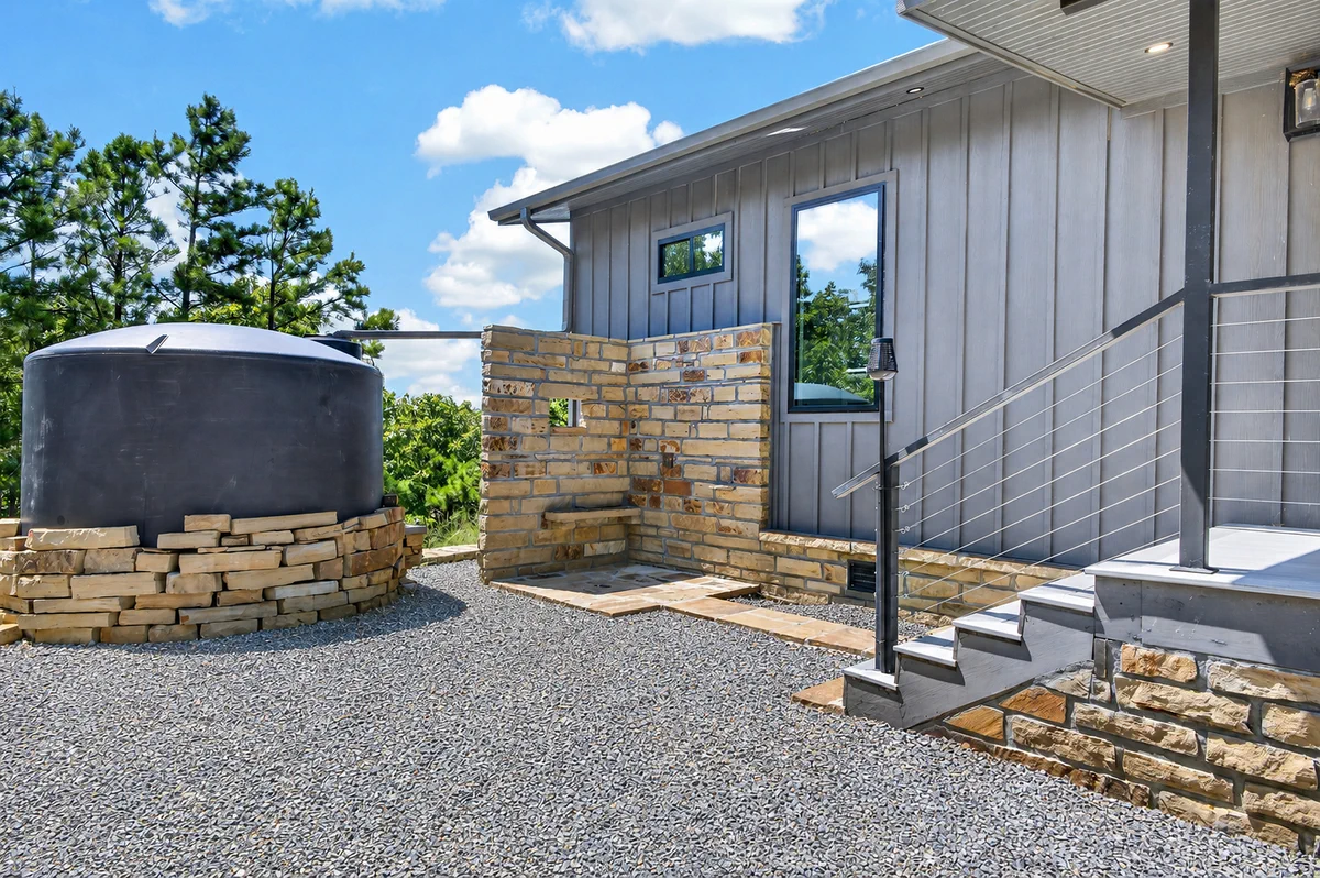 Stone outdoor shower and rainwater cistern at the mountain home