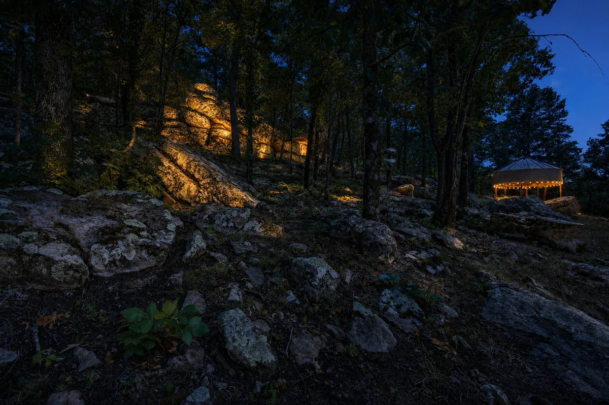 Stone path leading through the trees toward the home at night